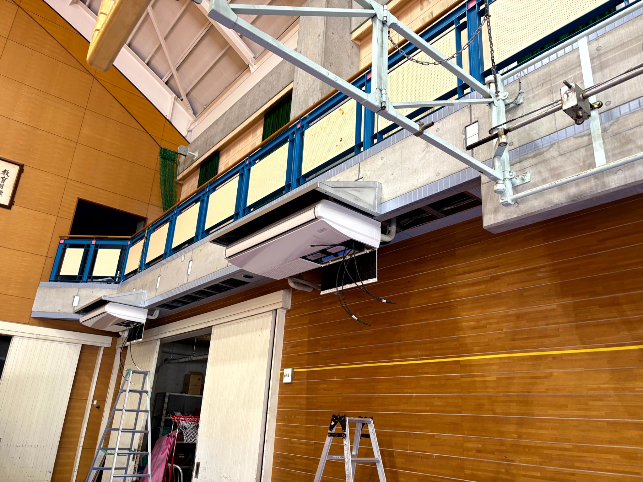 体育館内で空調設備を設置する作業